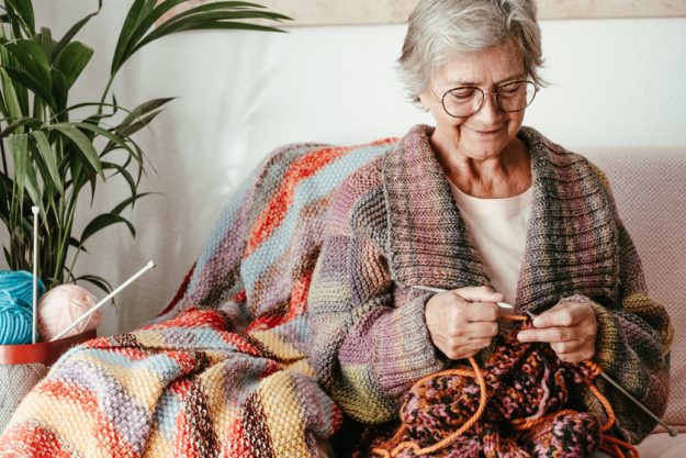 Senior mature woman sitting on sofa at home while knitting and l Crafting Activities For Your Elderly Parent With Dementia