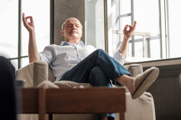 Senior hispanic man meditating on the sofa How Spirituality Benefits You In Your 60s