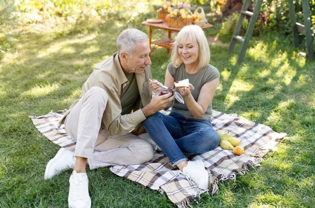 Cute retired couple having picnic in garden Cute retired couple having picnic in garden