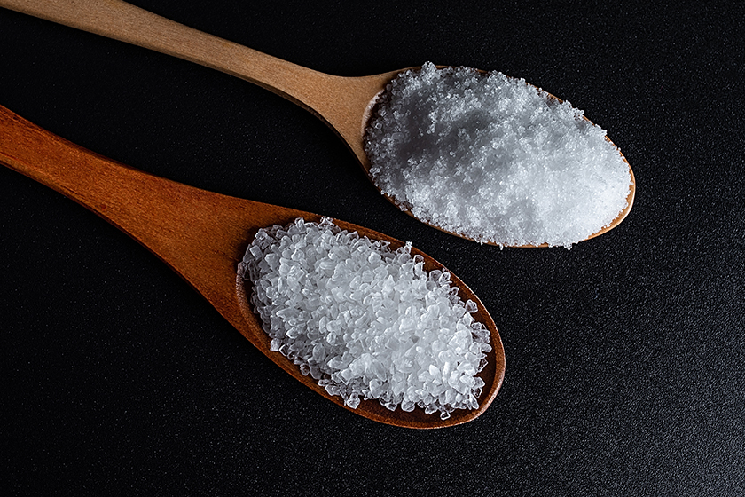 Coarse sea salt and fine salt on black background Coarse sea salt and fine salt on black background