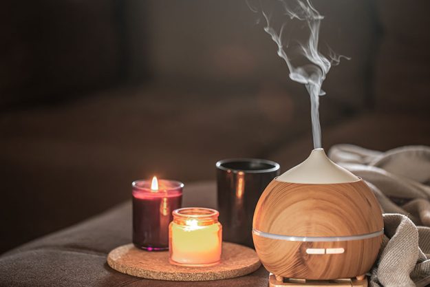 Oil diffuser on blurred background near burning candles