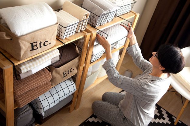 A woman is doing spring cleaning. Folds bedding, blankets, towel A woman is doing spring cleaning. Folds bedding, blankets, towel