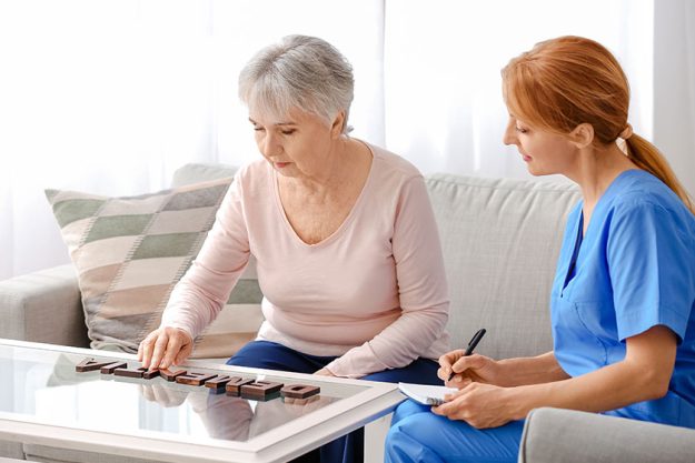 Elderly woman suffering from mental disability and caregiver in nursing home