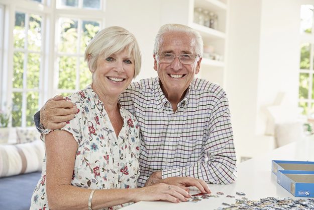 Senior-couple-doing-a-jigsaw-puzzle-at-home-smiling