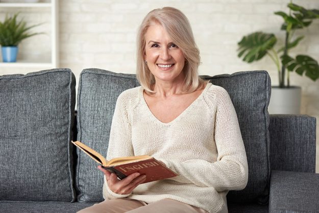 Beautiful 50 years old woman reading an English textbook