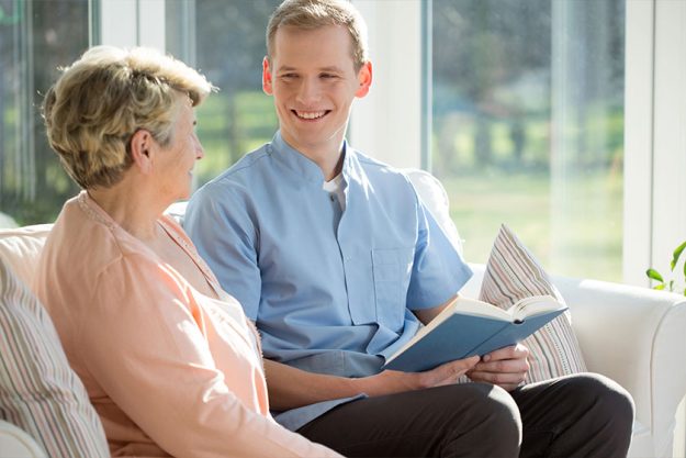 Man reading book with elderly woman Man reading book with elderly woman
