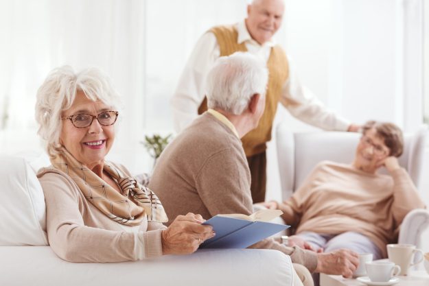 Elderly,Happy,Woman,Reading,A,Book,In,Common,Room