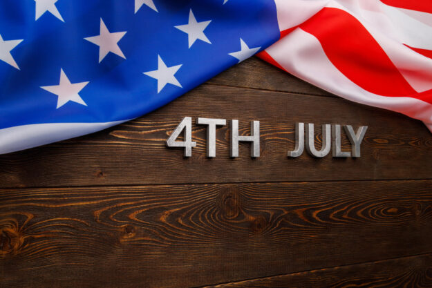 the words 4th july and crumpled usa flag on flat textured wooden surface background